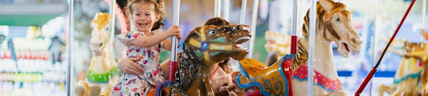 smiling girl riding a merry-go-round in Pasadena, TX