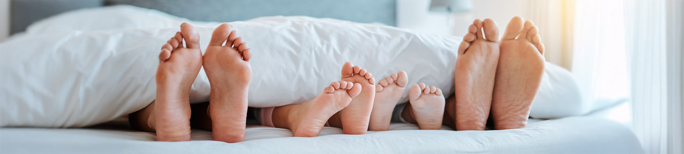 hotel bed and family sticking feet out from the comforter
