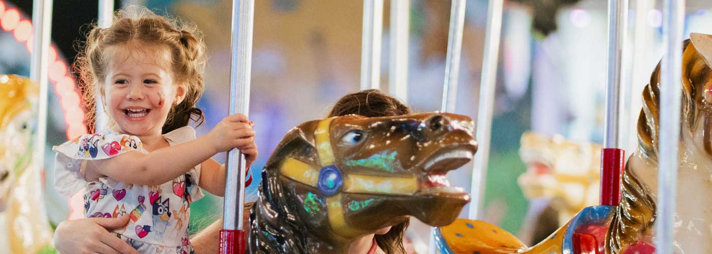 child riding a carousel at the county fair