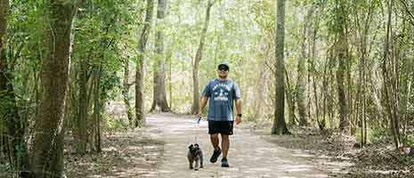 man walking his dog on a trail Armand Bayou Nature center in Pasadena, TX